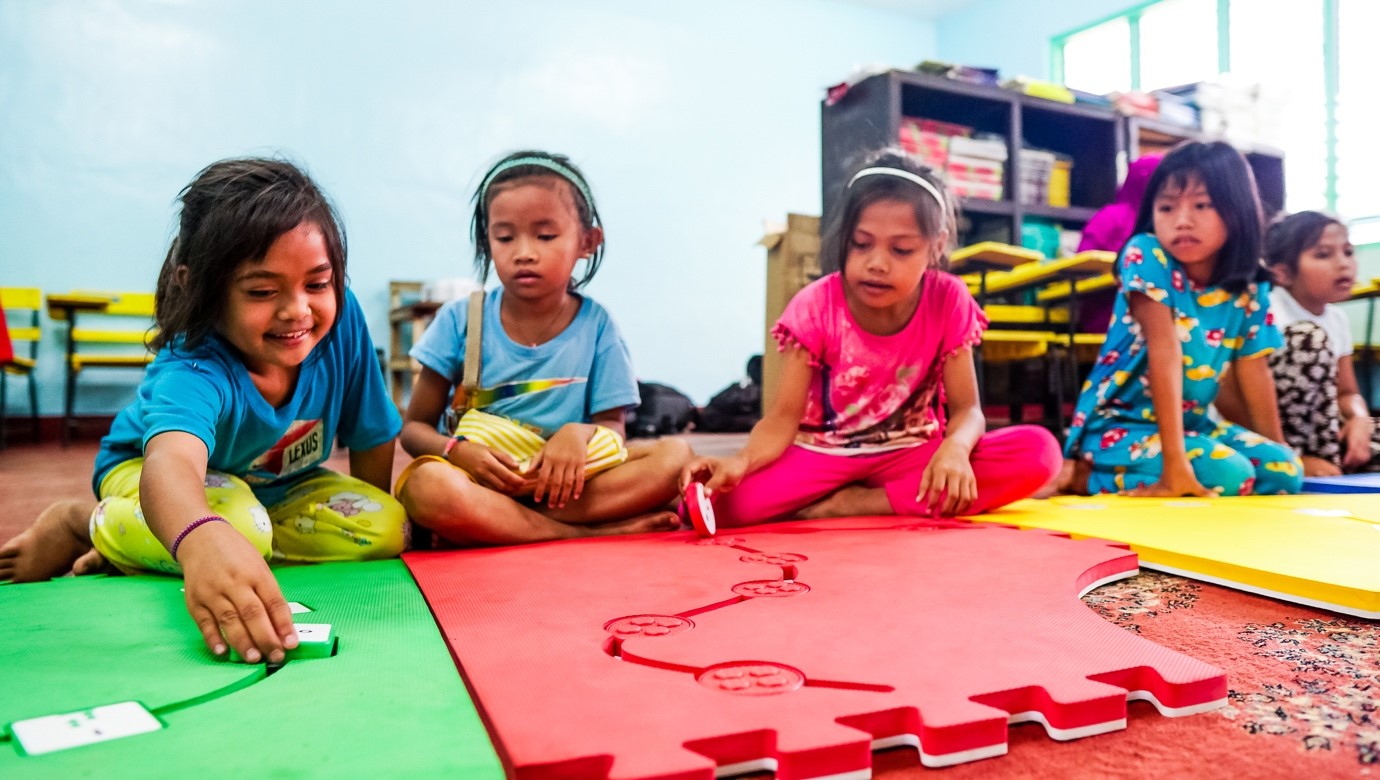 Photo: Children participating in a Reach & Match activity focused on fine motor skills and shape sorting